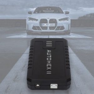 a black device on a road with a white car in the background